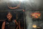 A woman stands in a smoke-filled kitchen hut in the village Ikenge, Cameroon, May 30, 2005.