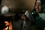Masto Devi, 80, sits by the fire in hte kithcen of her family home, in the Panthed Village, Himachal Pradesh, India, December 10, 2006.
