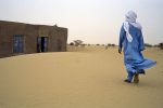 Climate change - mosque - A Tuareg man walks towards the mosque at prayer time in Kanak village, Niger, February 2005. Some scientist warn that the shifting of desert sand dunes could engulf currently productive land.